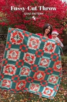 a woman holding a baby in front of a quilt