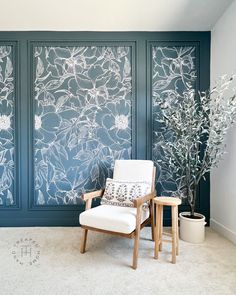 a white chair sitting in front of a blue wall with flowers and vines on it