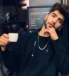 a man sitting in a chair holding a coffee cup