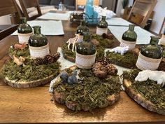 several wine bottles with animals on them sitting on top of moss covered slices of wood