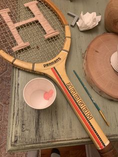 a tennis racket sitting on top of a table next to a cup and other items