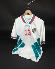 a soccer jersey hanging on a hanger in front of a black background with the number thirteen printed on it