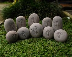 five rocks with faces carved into them on the grass