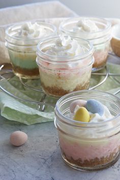 four small jars filled with desserts on top of a marble counter next to an egg