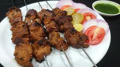 several skewers of meat and vegetables on a white plate with dipping sauces