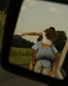 the rear view mirror shows a man carrying a woman on his back