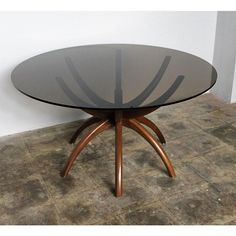 a glass table sitting on top of a floor next to a white wall and brown tile