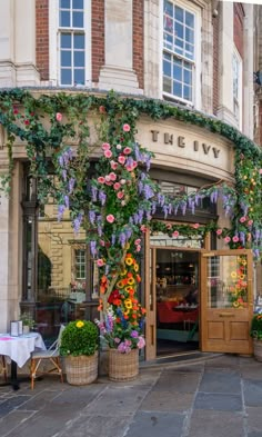 the ivy hotel is decorated with flowers and greenery on its front door, as well as an array of potted plants