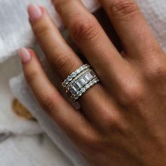 a woman's hand wearing a ring with three rows of diamonds on the band