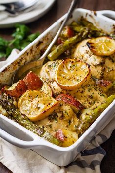 a casserole dish with chicken, asparagus and lemons in it