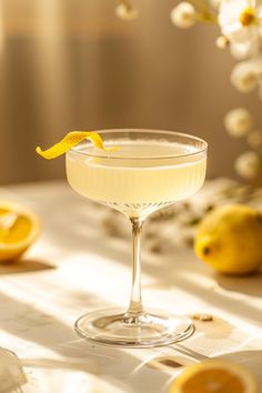 a glass filled with a drink sitting on top of a table next to lemons