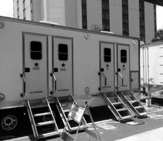 three portable restrooms are lined up on the side of the road in front of a tall building