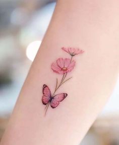 a pink flower and butterfly tattoo on the arm