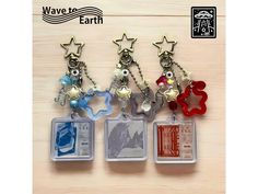 four different key chains with charms attached to them on a wooden surface, one is red and the other is blue