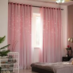 a bedroom with pink curtains and a bed in front of a window that has stars on it