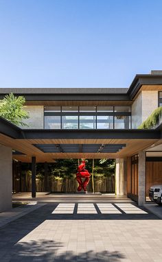 a large open courtyard with a red sculpture in the center and two cars parked on the other side