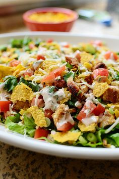 a white plate topped with a salad covered in cheese and toppings on top of lettuce