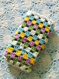 a crocheted cell phone case sitting on top of a doily