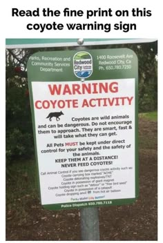 a sign that is posted on a pole in front of some grass and trees with the words warning coyole activity