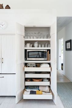 a kitchen with white cupboards and shelves filled with dishes on top of each other