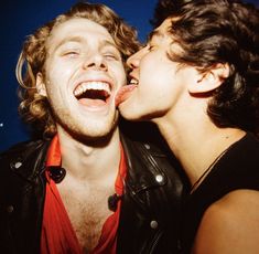 two young men are kissing each other with their mouths open