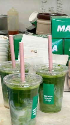 two green drinks with pink straws sitting on a counter