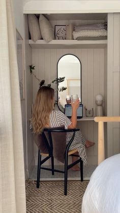 a woman sitting at a desk in front of a mirror