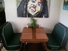 a table with two green chairs and a painting on the wall