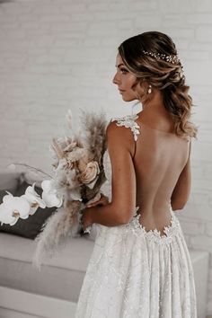 the back of a woman in a wedding dress with feathers on her head and flowers in her hair