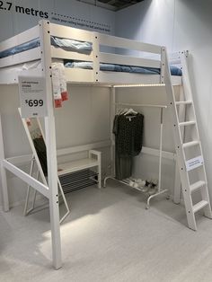 the bunk bed is white and has two ladders on each side, which are also used as a desk