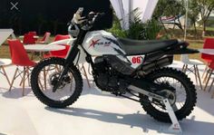 a white and black dirt bike parked on top of a cement floor next to red chairs