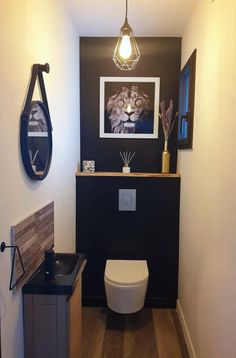 a bathroom with a white toilet sitting next to a wall mounted art on the wall