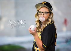 a girl blowing bubbles while holding a baseball in her hand and wearing glasses on top of her head