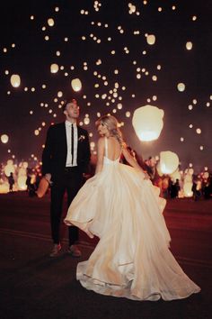 a bride and groom are standing in front of floating lanterns at their wedding reception on the night sky