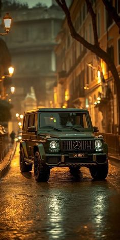 a green jeep is driving down the street at night with its lights on and it's hood up