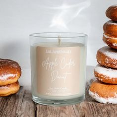 an apple cider donut sits next to a candle and some doughnuts