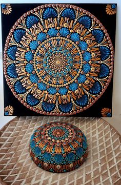 an artistic painting on the wall next to a round stool and ottoman cover with a decorative design