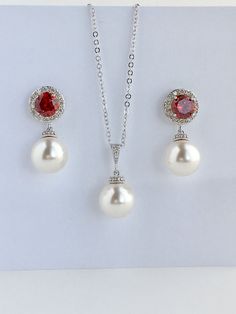 I've created this elegant red ruby cubic zirconia and pearl bridal jewelry set in rhodium plated brass setting and the set includes: # Earrings feature large 12mm Swarovski pearls that dangle from brilliant cut red ruby cubic zirconia with halo setting 12mm ear stud. Halo setting gives a brilliantly beautiful effect. Total length of the earrings is 2.8 cms. #Classic pearl bridal necklace and pendant set with rhodium plated brass peg and bail. Necklace features a pendant with large 12mm Swarovski Elegant Red Pearl Jewelry, Elegant Ruby Bridal Set For Wedding, Elegant Red Jewelry Sets For Wedding, Elegant Red Jewelry For Wedding, Elegant White Ruby Jewelry Sets, White Ruby Jewelry Sets For Wedding, Red Round Pearl Jewelry, White Ruby Jewelry Sets For Gift, Red Pearl Drop Jewelry For Anniversary