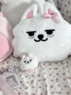 a white stuffed animal sitting on top of a bed next to a pink teddy bear