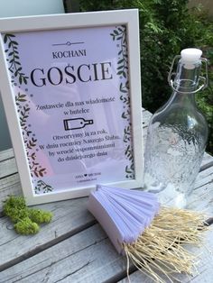 there is a bottle and some papers on the table next to it, which has been placed in front of a sign that says goscie