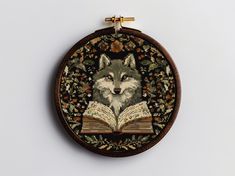 an embroidered wall hanging with a wolf reading a book