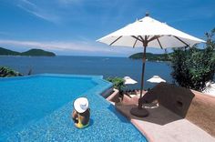 an outdoor pool with umbrellas and chairs next to the water in front of it