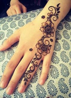 a woman's hand with a henna tattoo on her left hand and an intricate flower