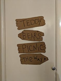 three wooden signs that say teddy bears, picnic and the way on a white door