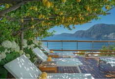 an outdoor deck with white lounge chairs and lemon trees over looking the ocean in italy