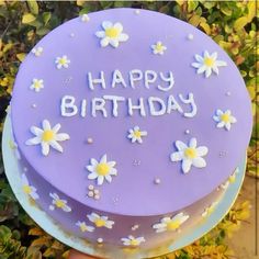 a purple birthday cake with daisies and the words happy birthday written on it in white frosting