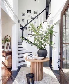 an entryway with stairs and a table in the center, surrounded by pictures on the wall