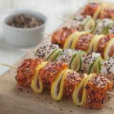 several skewers of sushi with lemons, cucumbers and black sesame seeds