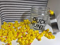 a jar filled with yellow rubber ducks sitting next to a pile of smaller plastic chicks