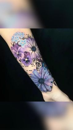 a woman's arm with purple and blue flowers on the inside of her arm